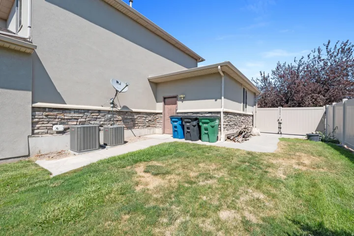Spacious backyard with established lawn and mature landscaping, complemented by a stone-accented exterior, utility shed with storage, and fenced perimeter for privacy and security