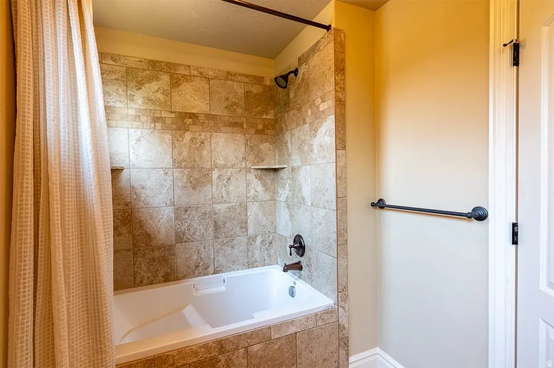 Bathtub with a tiled surround, tiled wall with decorative band and built-in niches, and an oil-rubbed bronze shower fixture