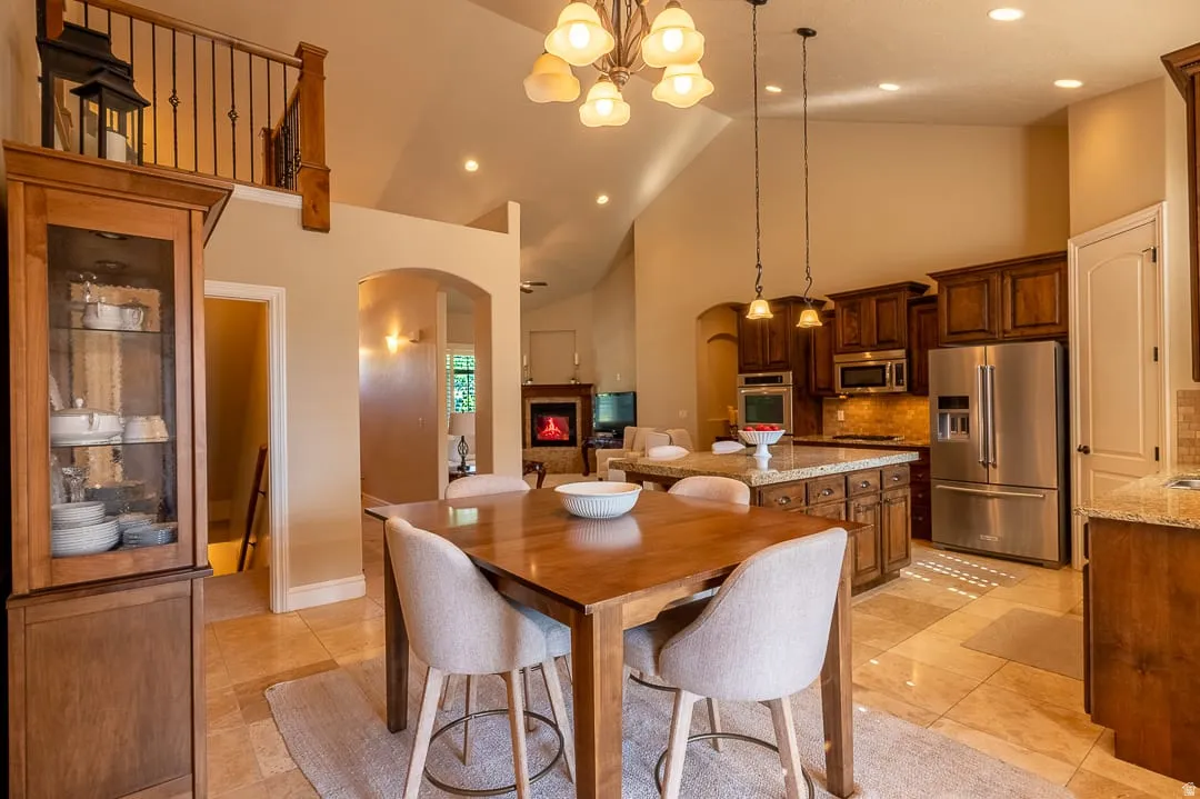 Open-concept living area with vaulted ceilings, a kitchen island featuring granite countertops, and stainless steel appliances