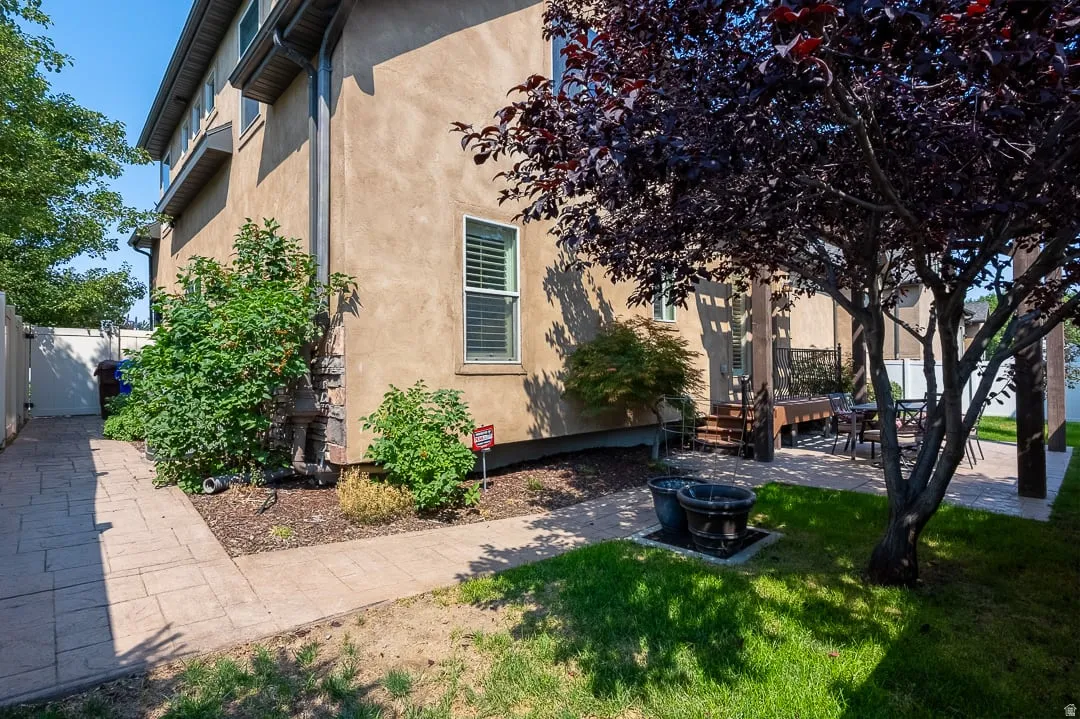 Exterior stucco finish, decorative stone accents, mature landscaping, paved patio, and a privacy fence