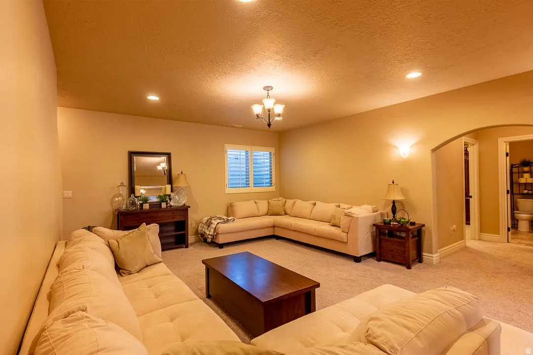 Recessed lighting throughout, arched doorway, chandelier, wall sconces, and a window with blinds