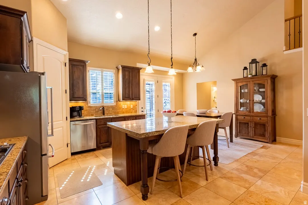 Kitchen featuring granite countertops, dark wood-finish cabinetry, stainless steel appliances, and tile flooring