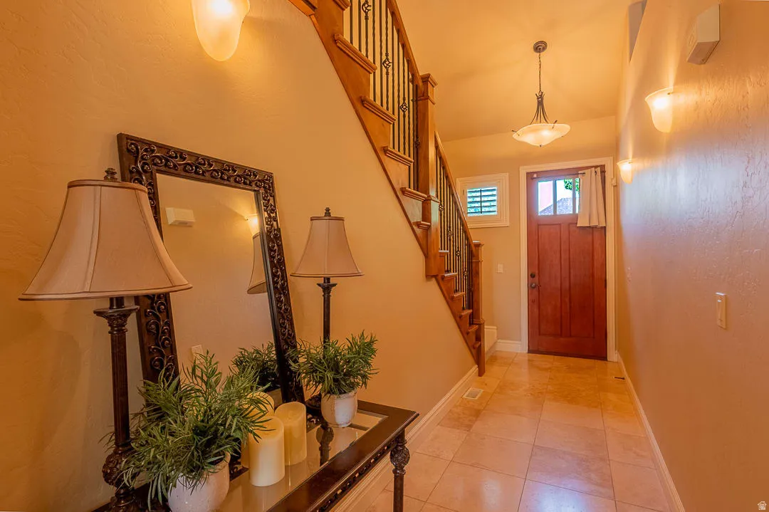 Hardwood staircase with iron balusters, tiled flooring, wood-paneled entry door, and a built-in light fixture
