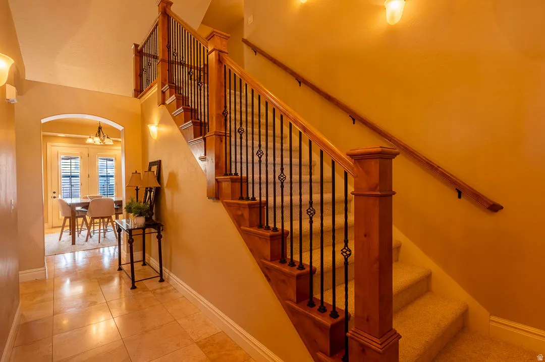 Staircase featuring wood newel posts, wood handrails, and wrought iron balusters