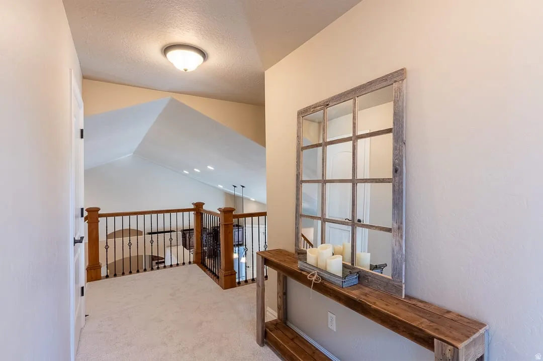 Carpeting throughout, wood-finish and wrought iron railing, vaulted ceilings, and a flush mount ceiling light