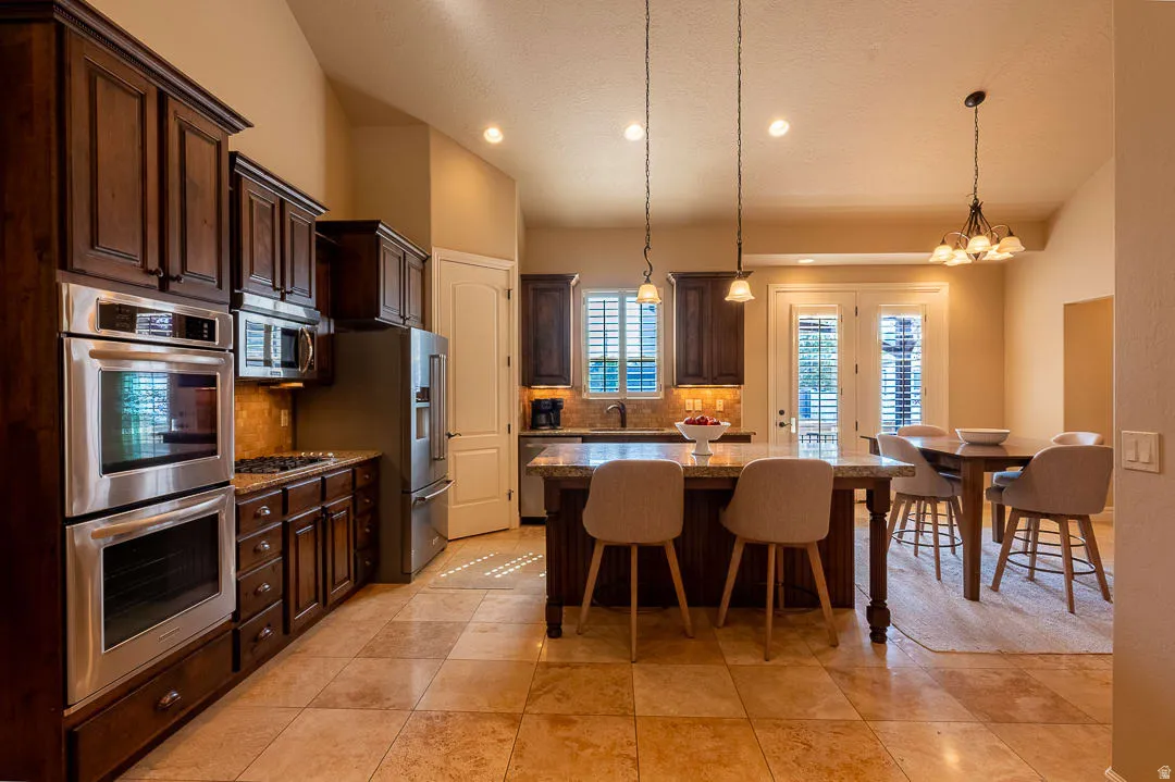 Kitchen featuring rich wood cabinetry, stainless steel appliances, a center island with countertop seating, and tile flooring