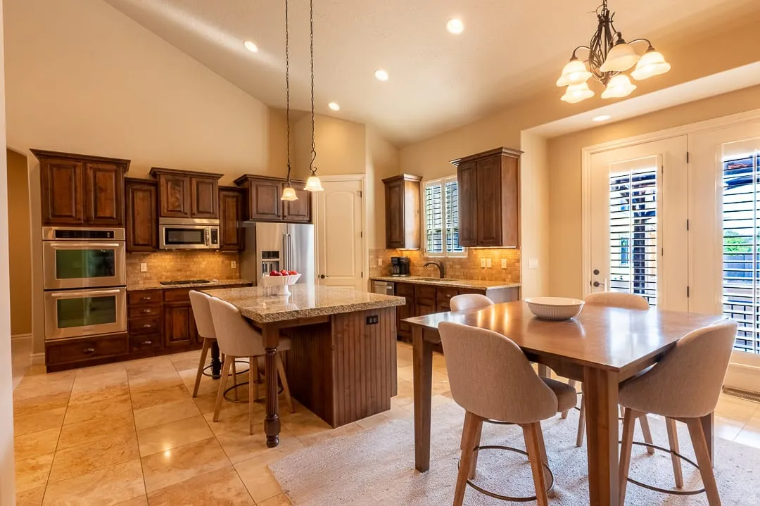 Kitchen featuring vaulted ceilings, wood cabinetry, stainless steel appliances, a center island with countertop, and tile flooring