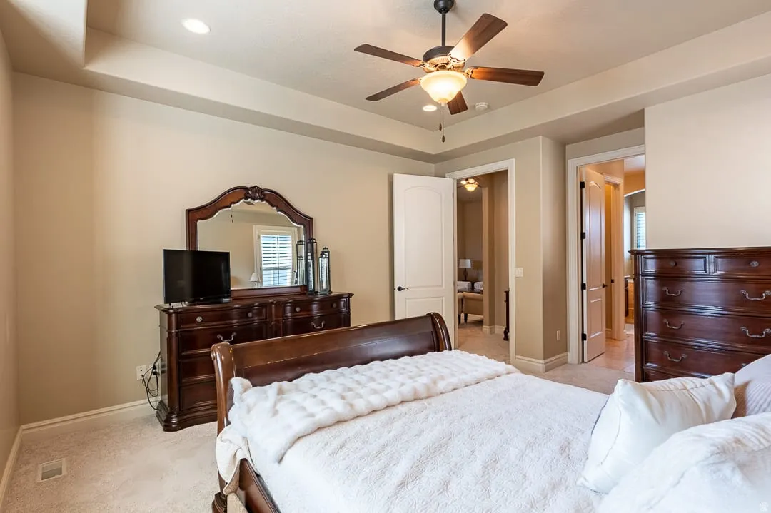 Tray ceiling with recessed lighting, ceiling fan, and carpeted flooring