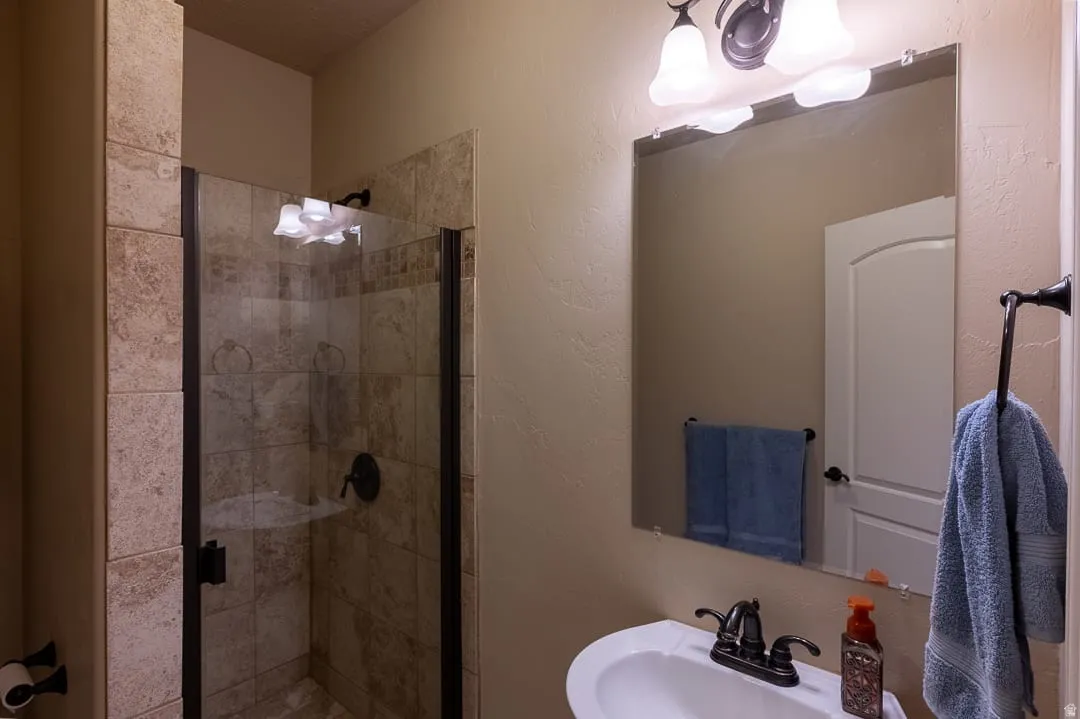 Tiled shower enclosure with a clear glass door, featuring a bronze-finish shower fixture