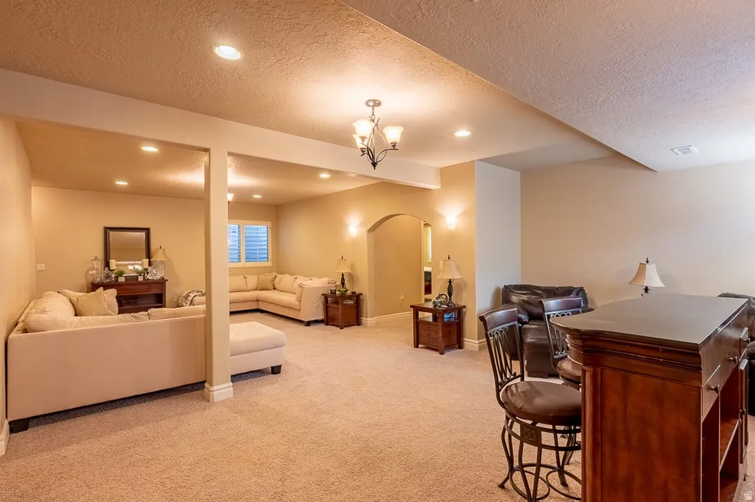 Recessed lighting, arched doorway, chandelier, built-in bar, and window with blinds