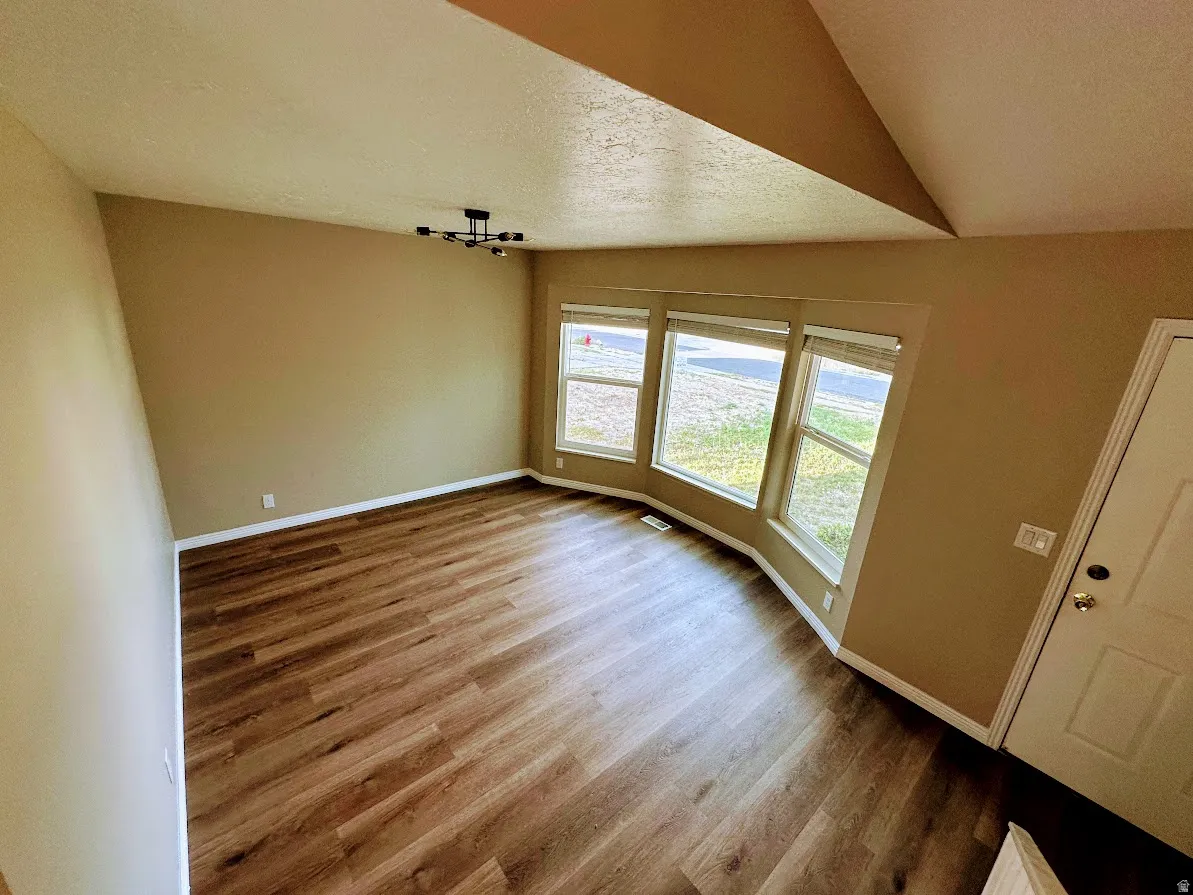 Wood-finish flooring throughout, bay windows, contemporary lighting fixture, and a neutral color palette