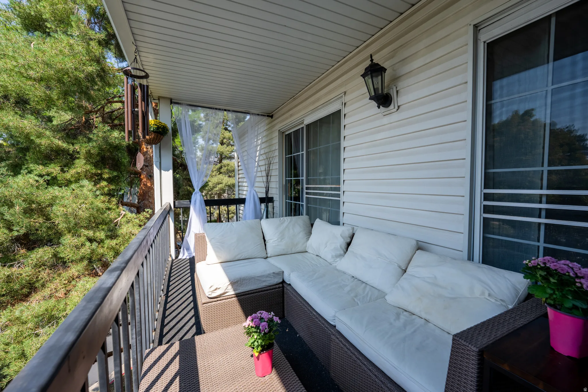 Covered balcony featuring white siding, a built-in light fixture, and two sliding glass doors