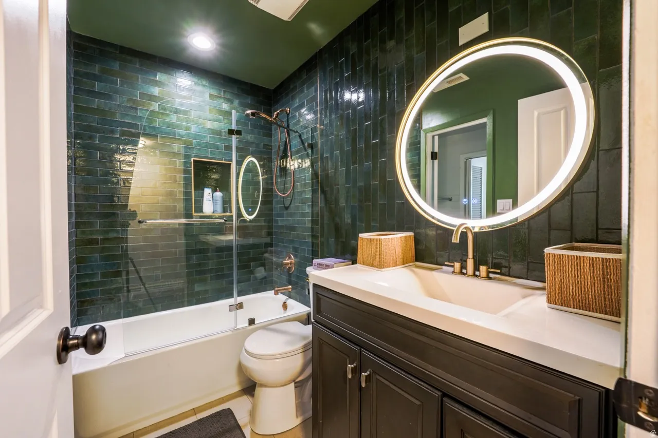 Spa-inspired bathroom featuring a walk-in shower with subway tile surround and frameless glass enclosure, dual illuminated round mirrors, floating vanity with white quartz countertop, and matte black hardware accents