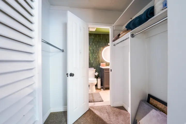 Carpeted hallway with built-in storage and a louvered door