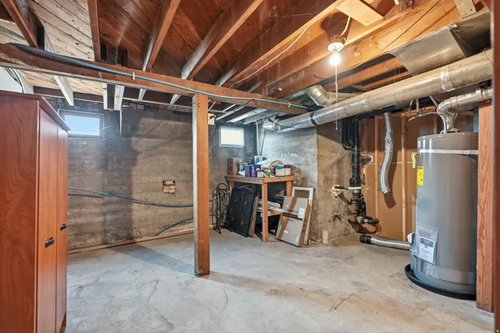 Exposed wood beam ceiling, concrete foundation walls, concrete flooring, and water heater