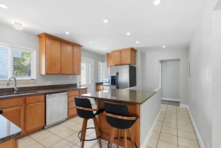 Kitchen featuring light wood cabinetry, stainless steel appliances, granite countertops, and recessed lighting