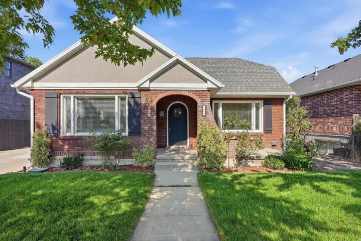 Brick and stucco exterior with an arched entryway, gabled roofline, and established front landscaping