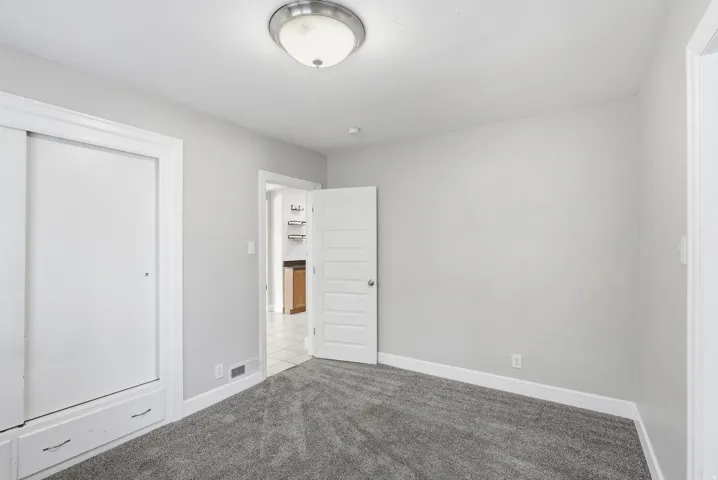 Neutral wall color, wall-to-wall carpeting, overhead flush-mount lighting, white trim, and a white interior door