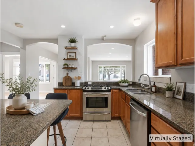 Kitchen featuring wood cabinetry, stainless steel appliances, granite-style countertops, and tile flooring