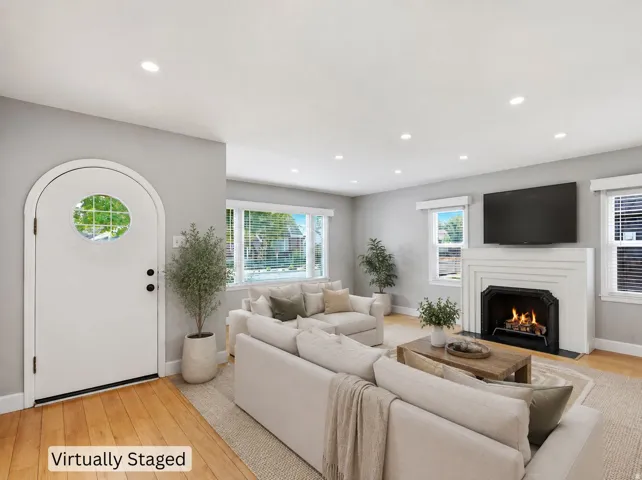 Hardwood-style flooring, a decorative fireplace with a substantial mantel, recessed lighting, an arched entry door with circular glazing, and multiple windows