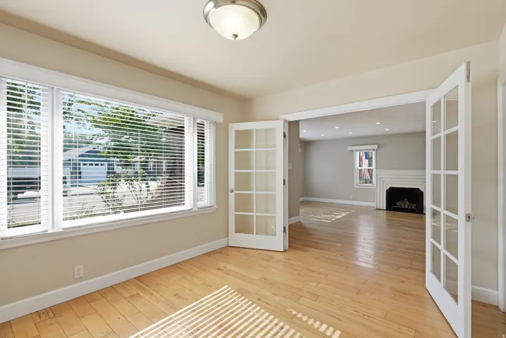 Hardwood flooring throughout, multiple windows with blinds, recessed lighting, and a fireplace with a mantel