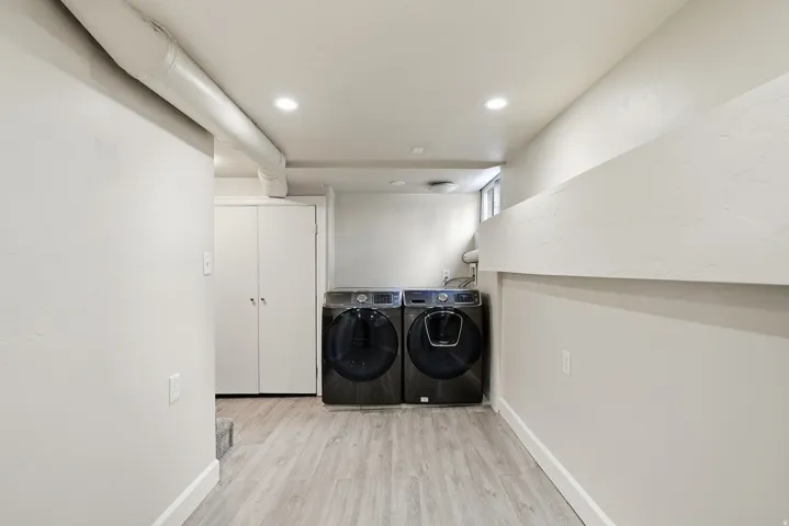 Laundry area featuring light wood-finish flooring, recessed lighting, and bi-fold closet doors