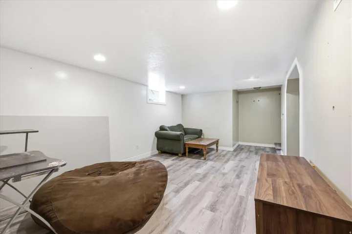 Recessed lighting, light gray wood-finish flooring, and a window for natural light