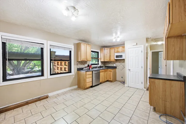 Kitchen featuring tile flooring, wood cabinetry, stainless steel dishwasher, and a built-in microwave