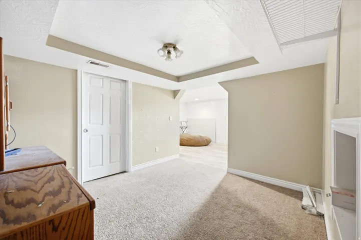 Recessed ceiling feature, neutral wall tones, textured ceiling, six-panel interior door, built-in shelving