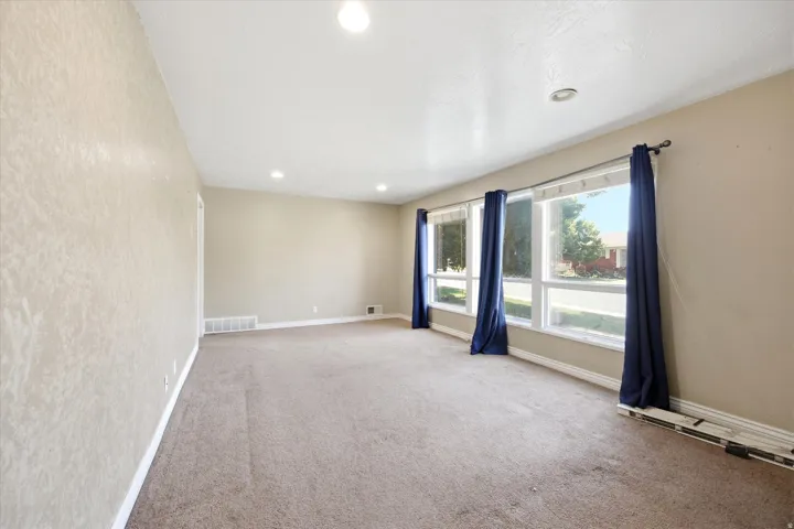 Recessed lighting, large windows, and neutral carpeting
