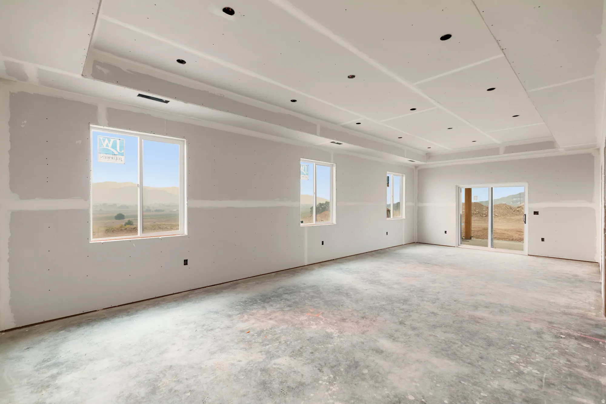 Tray ceiling with recessed lighting, multiple windows, and a sliding glass door