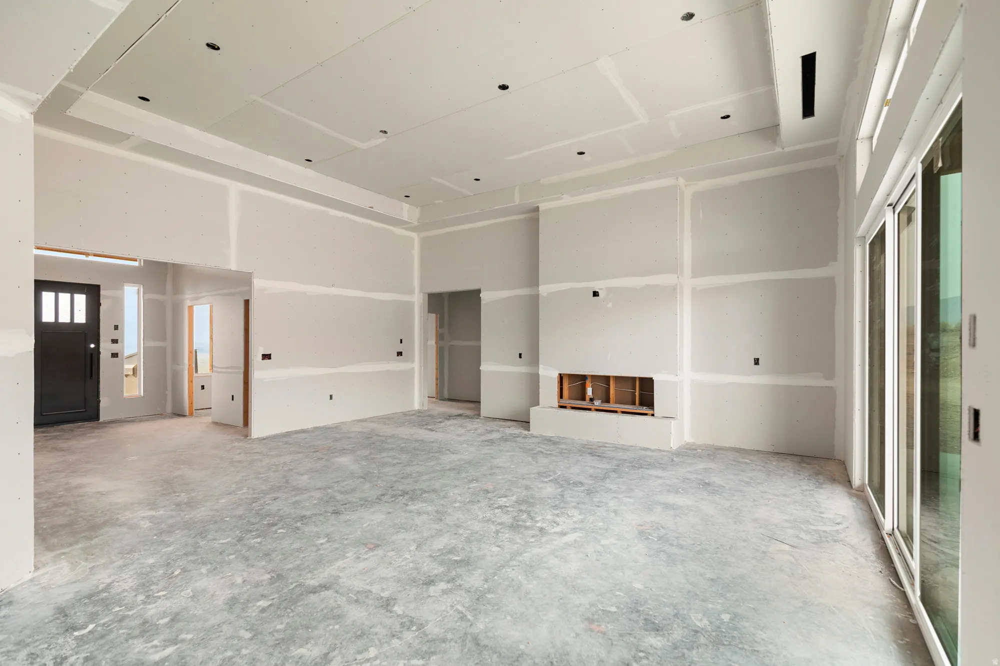 Spacious unfinished interior featuring a tray ceiling, recessed lighting, and a built-in fireplace structure