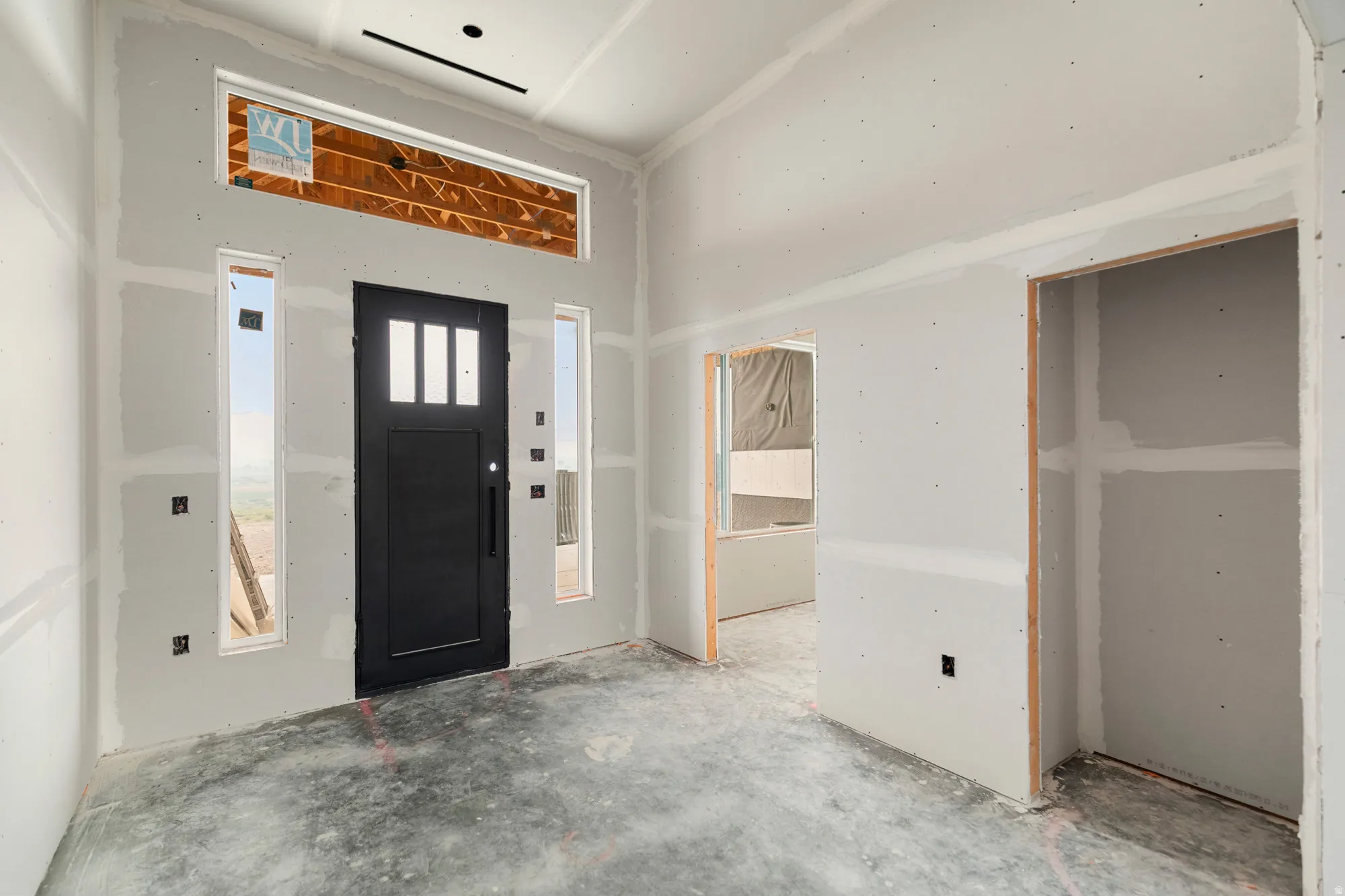 Black entry door with vertical glass inserts, flanked by two vertical windows, and a horizontal transom window above