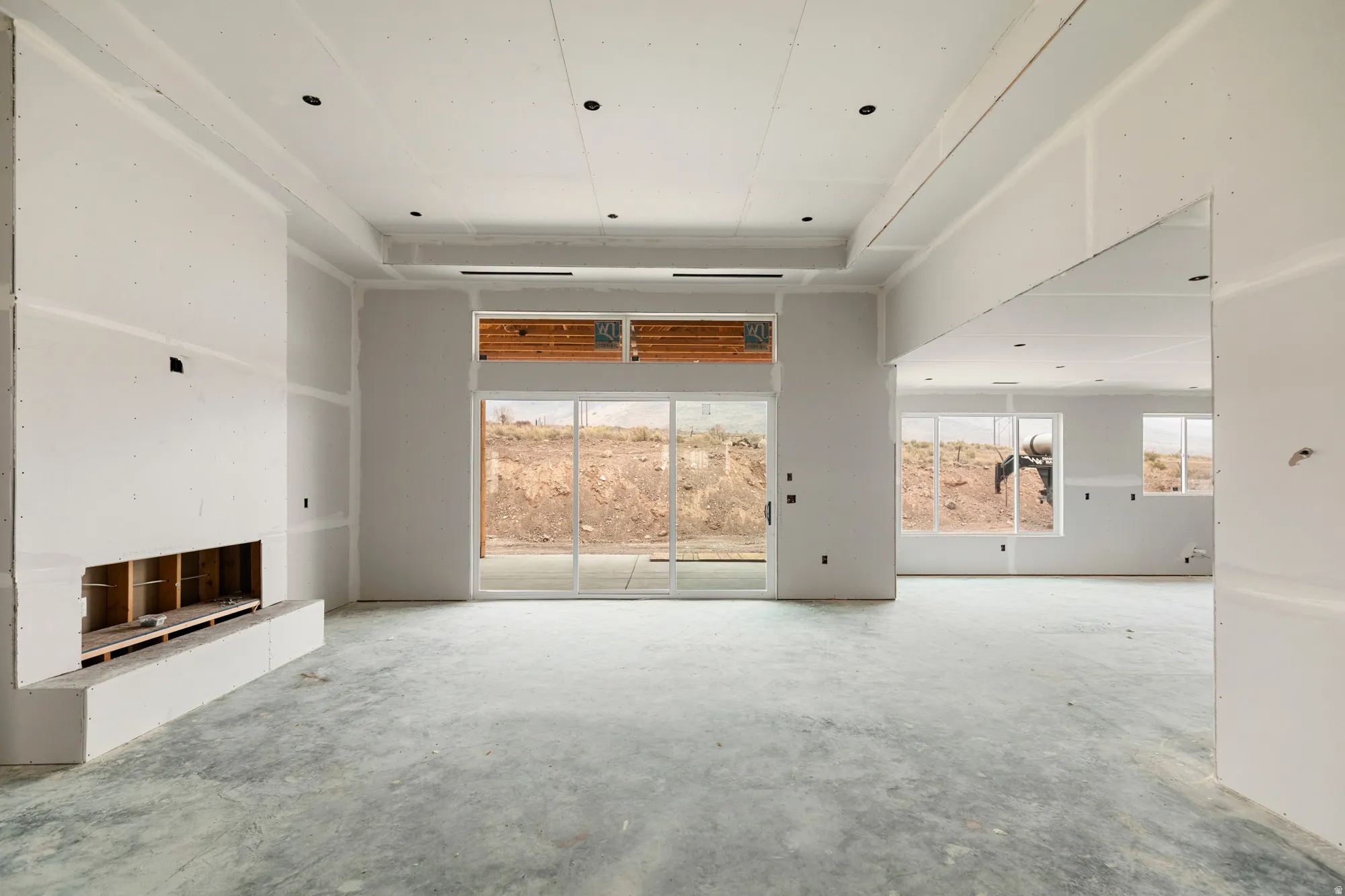 Expansive interior featuring a built-in fireplace, sliding glass doors, multiple windows, recessed lighting, and a tray ceiling