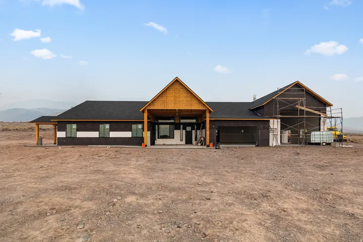 New construction residence featuring a prominent gabled entry, dark exterior siding, and a dark shingle roof