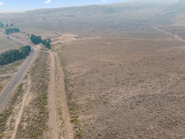 Expansive undeveloped land featuring a paved road and natural vegetation