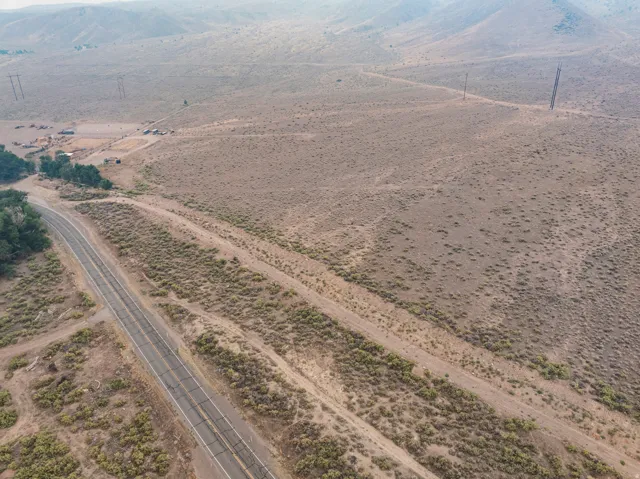 Expansive undeveloped terrain featuring scattered low-lying vegetation and a paved road