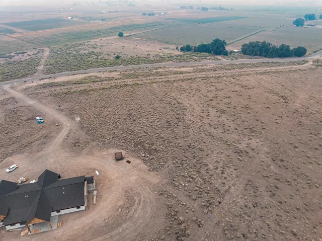 Expansive undeveloped land with a partially constructed structure, featuring a dark shingle roof and covered entry