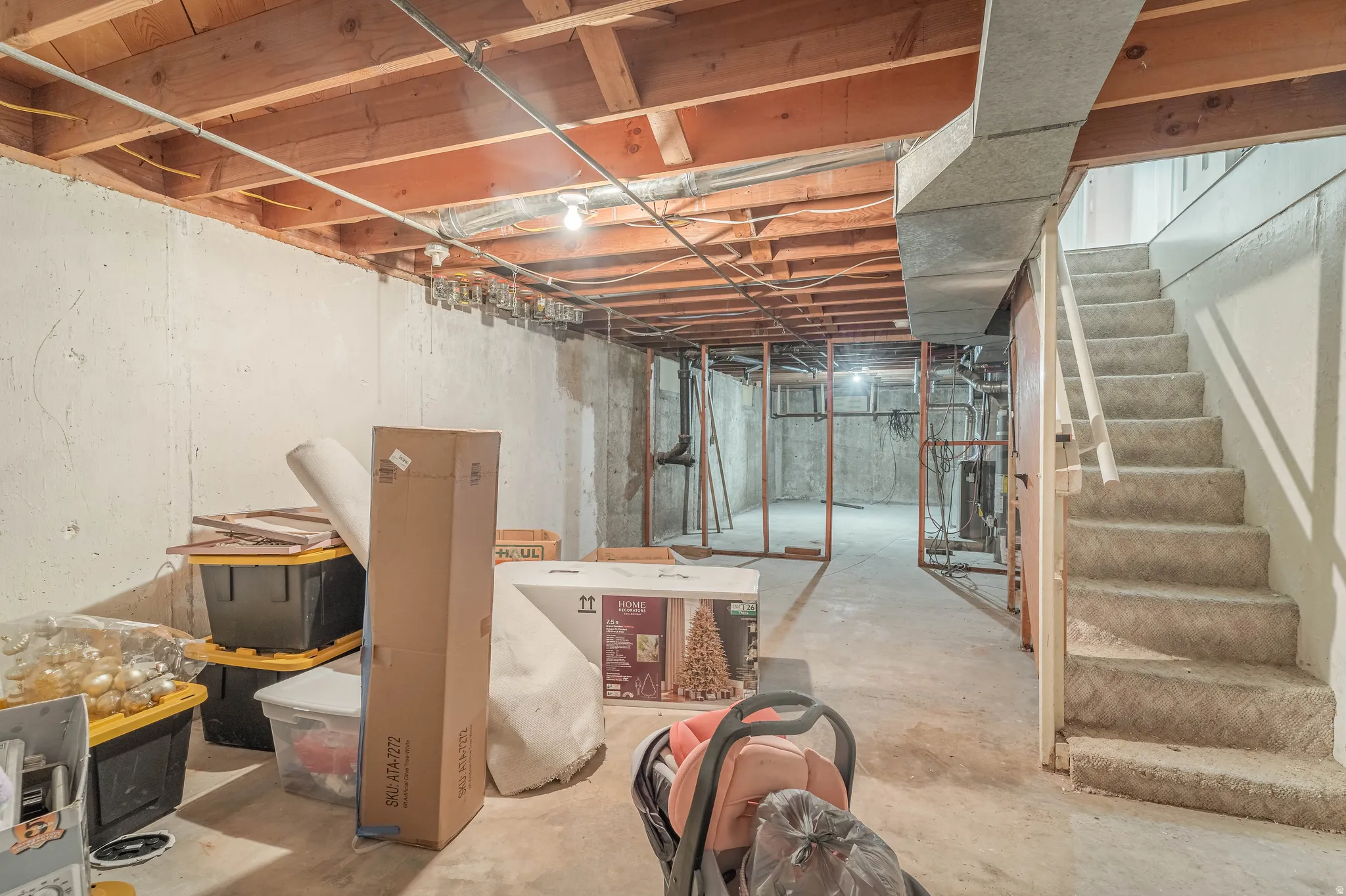 Unfinished basement space with exposed wood-beam ceiling, concrete flooring, and framed partition walls