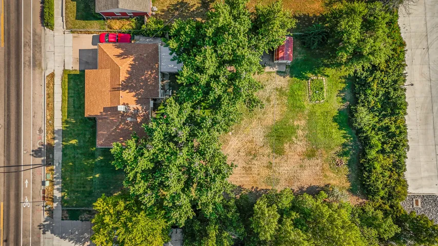 Expansive property featuring a gabled roofline, mature trees, a defined driveway, a separate shed structure, and an established garden plot