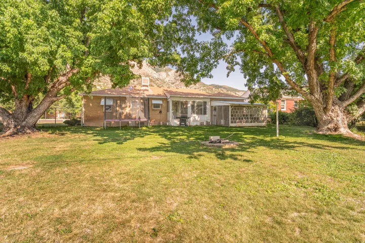 Charming brick residence set on expansive grounds featuring mature shade trees, a manicured lawn, and a covered front porch