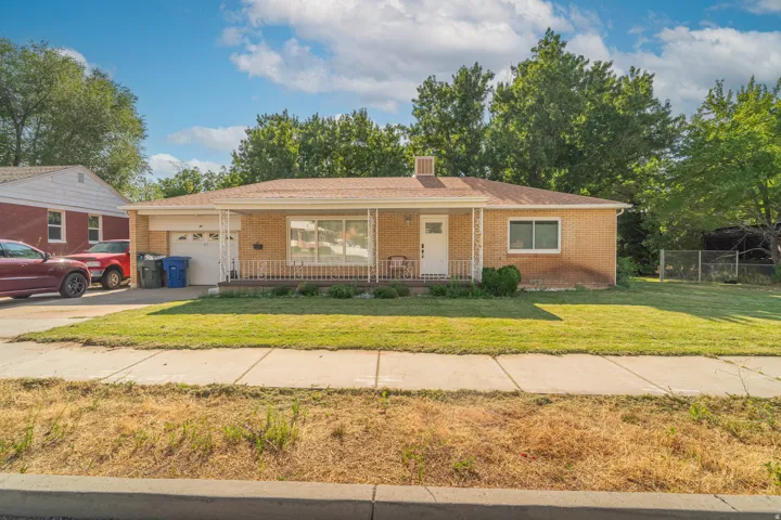 Charming brick ranch home featuring a covered front porch, single-car garage, and manicured lawn framed by mature landscaping
