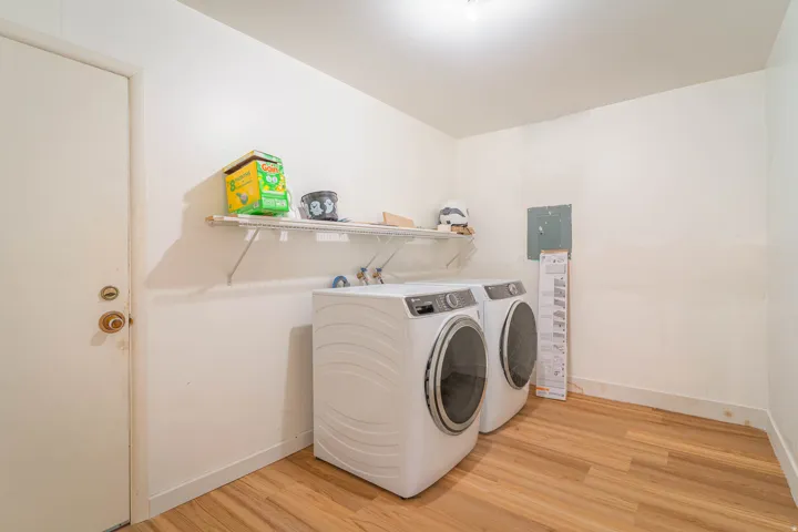 Dedicated utility space featuring wood-finish flooring, white walls, and a white ceiling