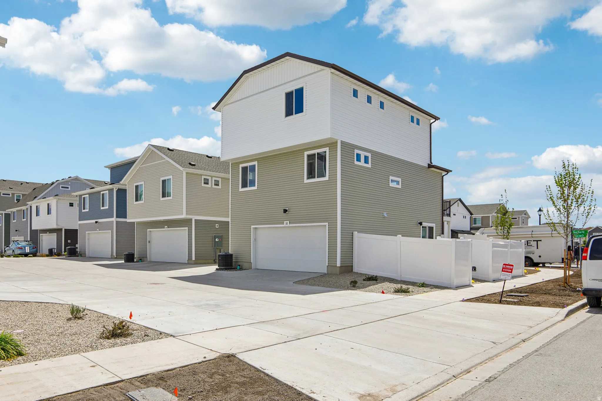 Two-story residence with a single-car garage, light-toned siding, and a partial white privacy fence