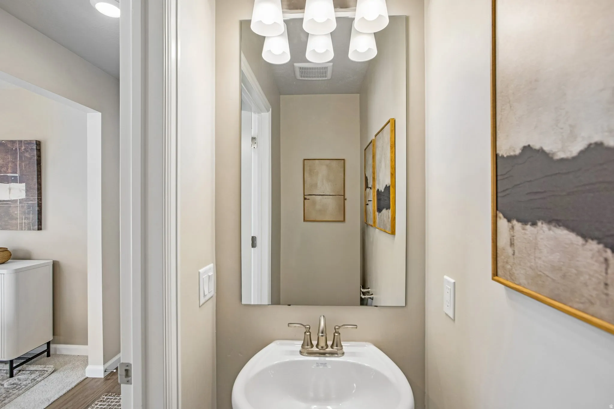 Pedestal sink with brushed nickel faucet, large vanity mirror, and overhead lighting fixture