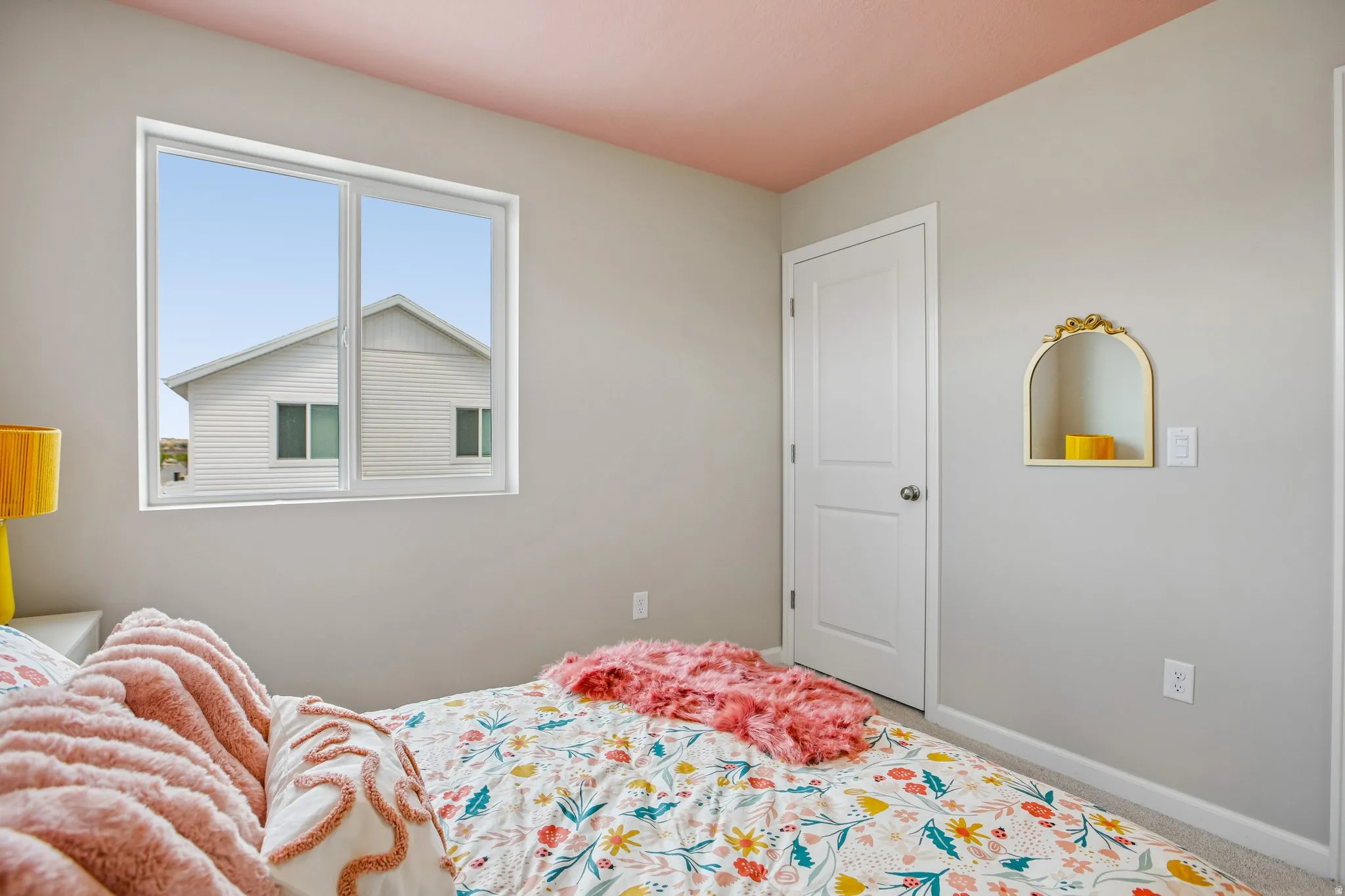 White trim window, white interior door with a silver knob, wall-mounted decorative niche with a gold-tone frame, and light gray wall paint