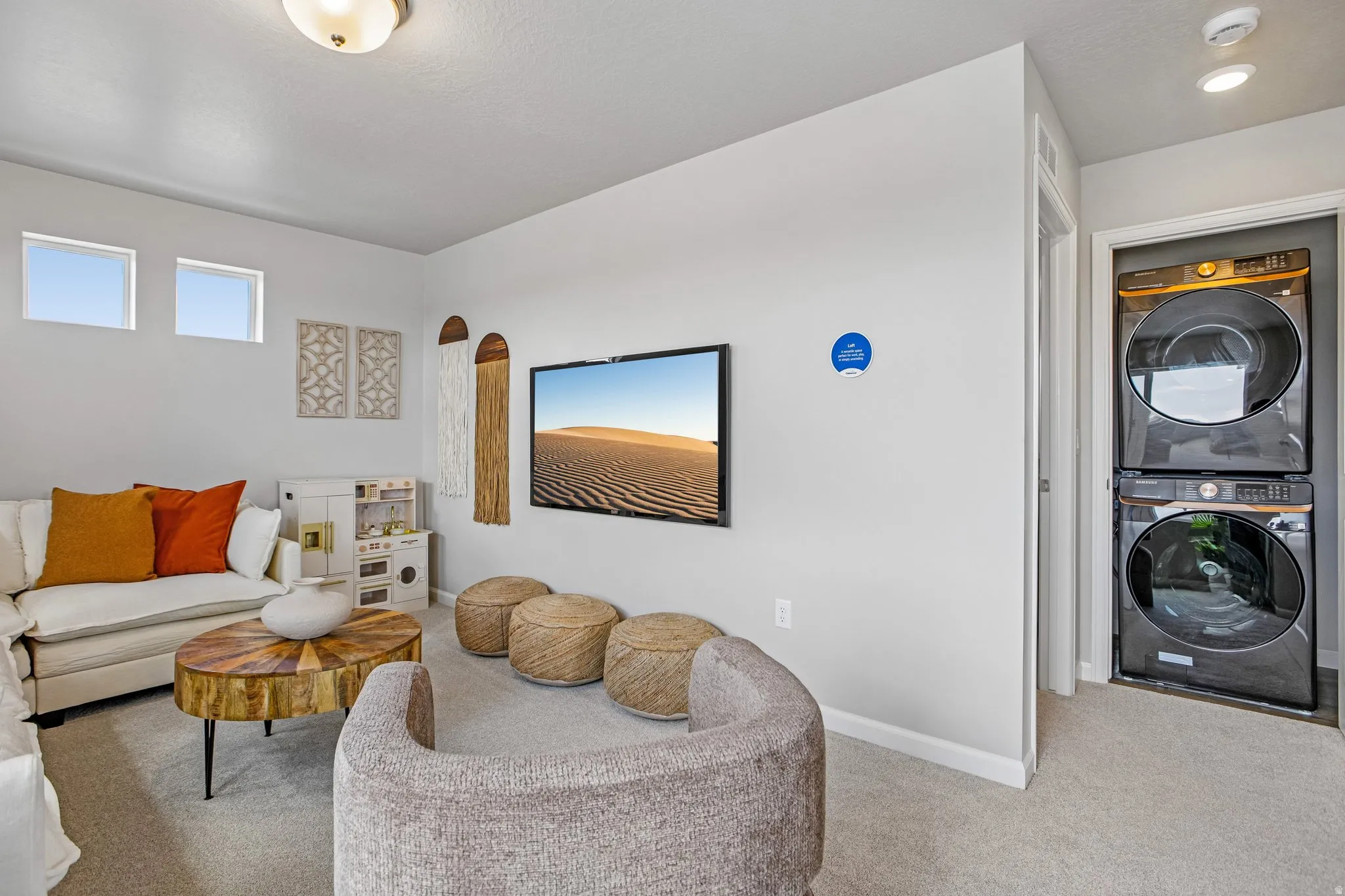 Carpeted room with a ceiling-mounted light fixture, two small rectangular windows, and a built-in stacked washer and dryer unit