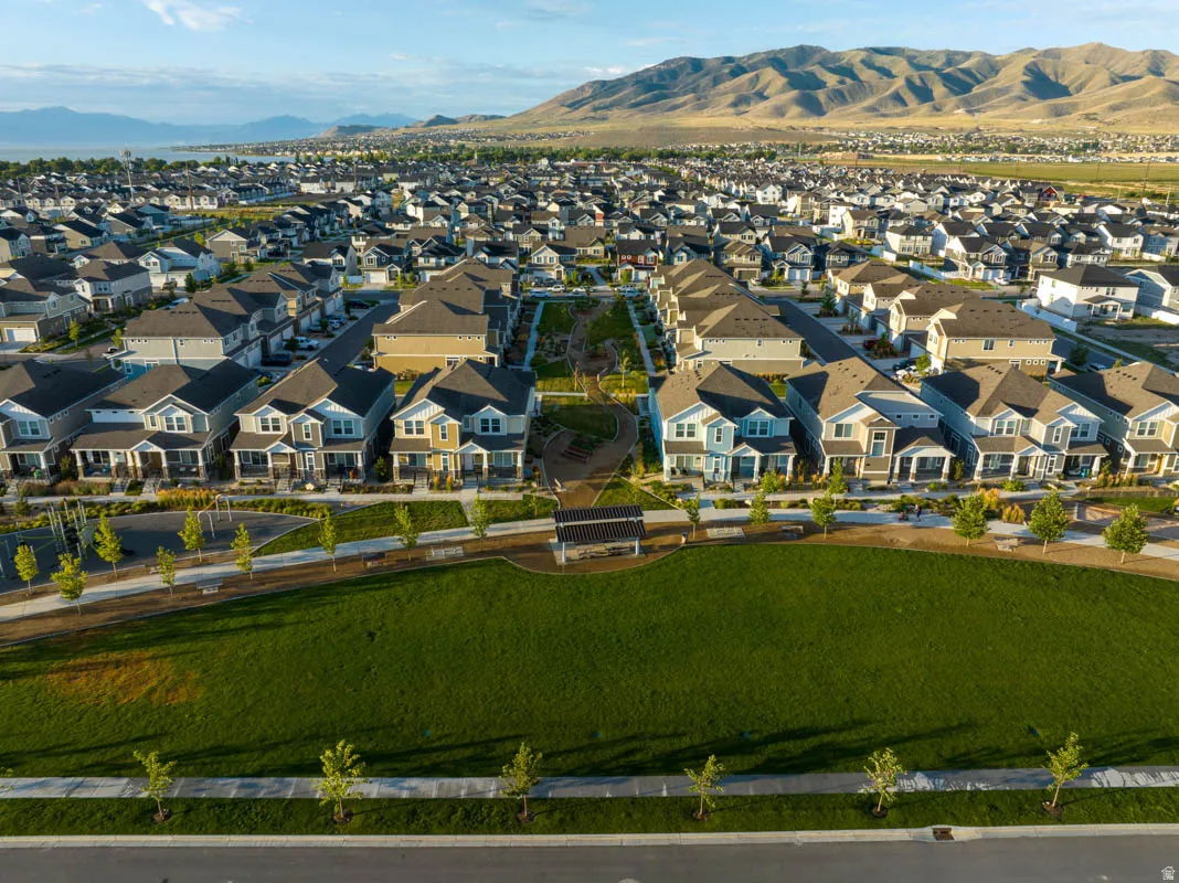 Expansive green space featuring a paved walkway, mature trees, and a mountain backdrop