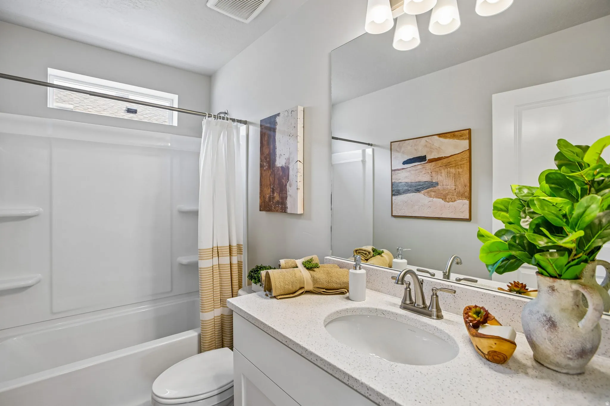 Integrated shower and tub combination, white vanity with an undermount sink, large vanity mirror, and overhead lighting fixture