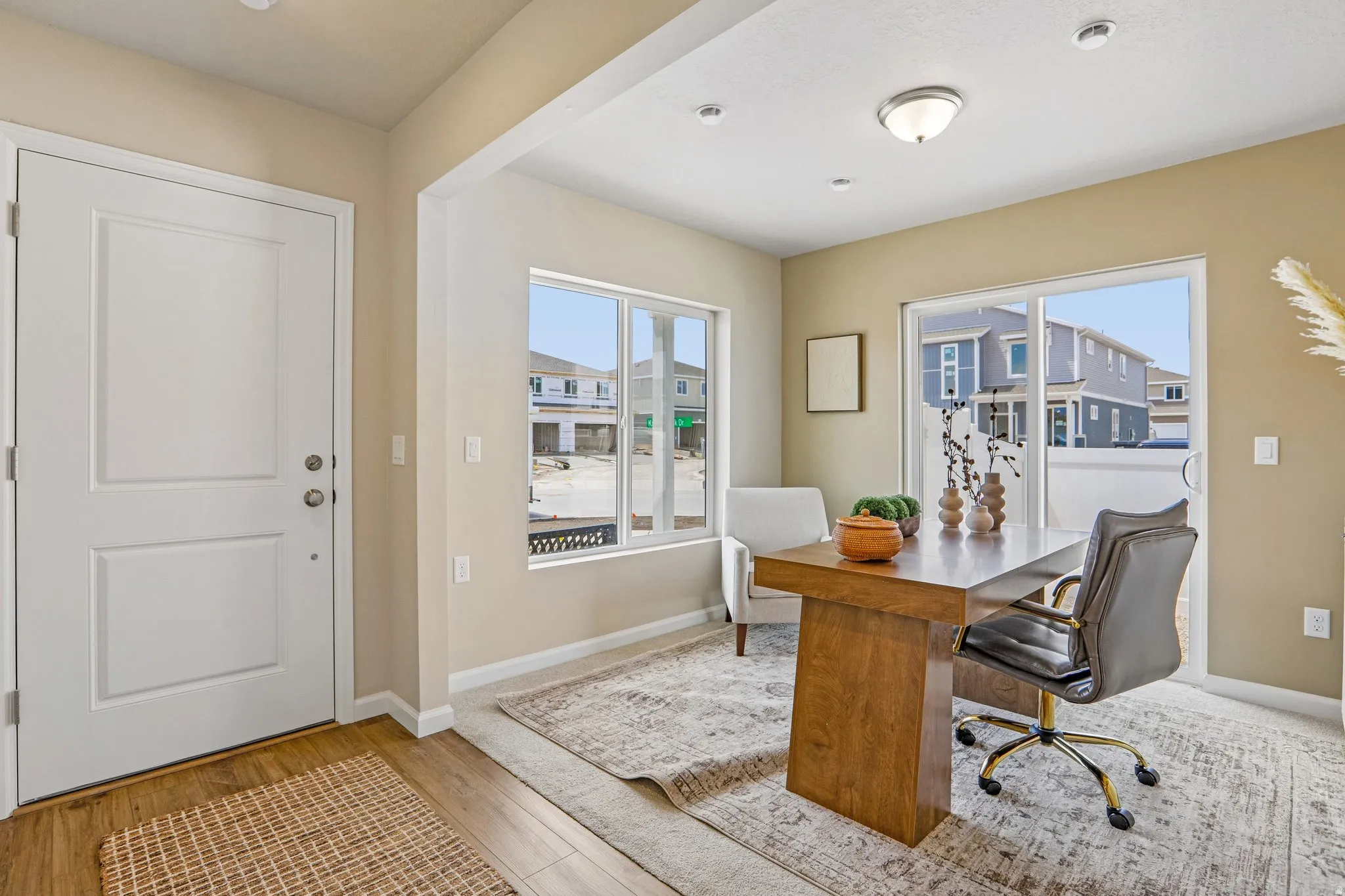 Entry area with wood-finish flooring, a solid panel entry door, recessed lighting, and a separate room featuring a large window and sliding glass door